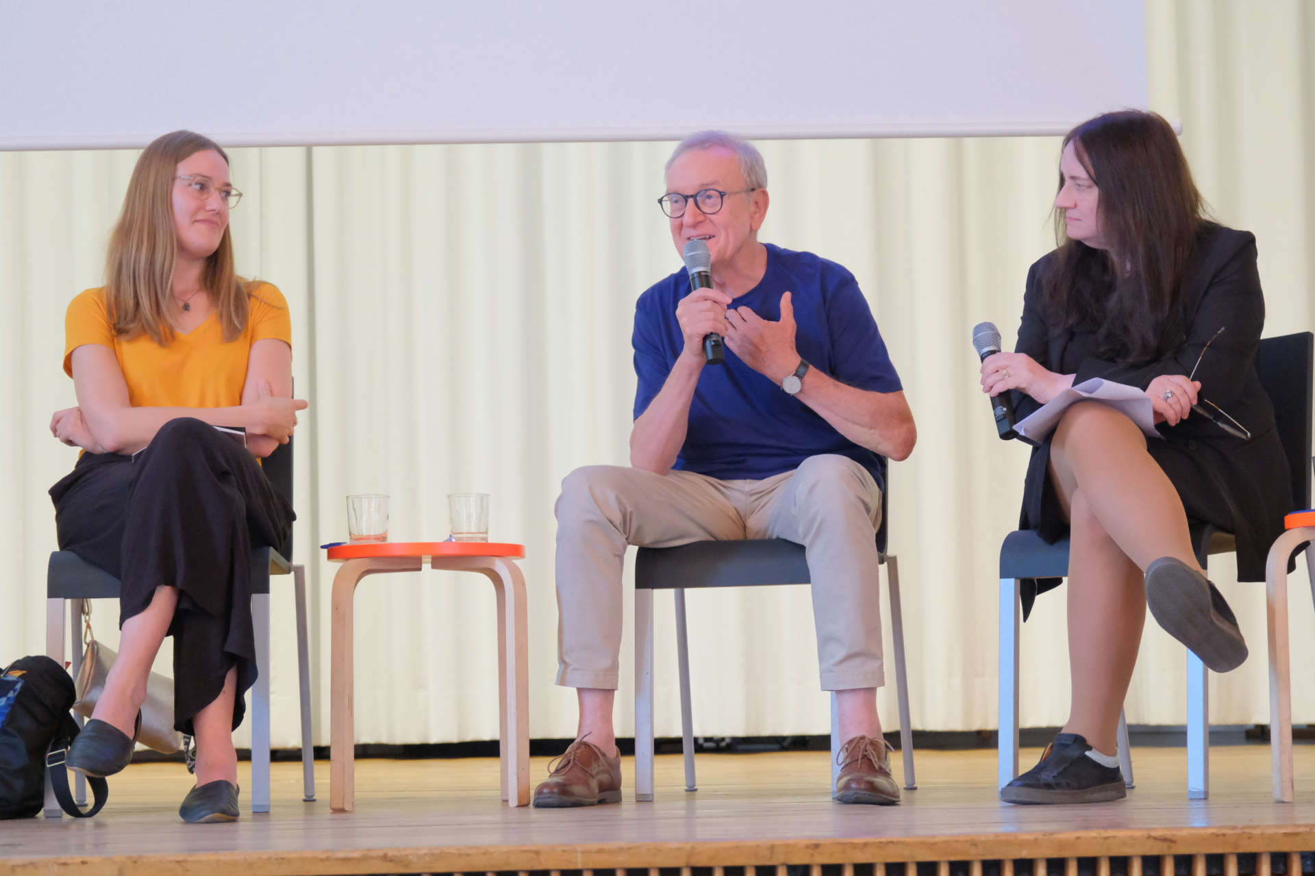 Das Foto zeigt Johanna Stapelfeldt (links), den Regisseur Günter Jeschonnek (Mitte) und Jutta Braun (Moderatorin) auf dem Podium sitzend in der Aula der KFM während des Symposiums "Kultur im Umbruch" am 4.6.2026 in Berlin-Weißensee.