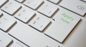 Ausschnitt einer Comuptertastatur, auf der Enter-Taste steht "apply now"