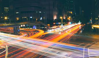 Aufnahme einer verkehrsreichen Kreuzung in Taipei bei Nacht, durch die lange Belichtungszeit hinterlassen die Lichter der Fahrzeuge rote und weiße Spuren.