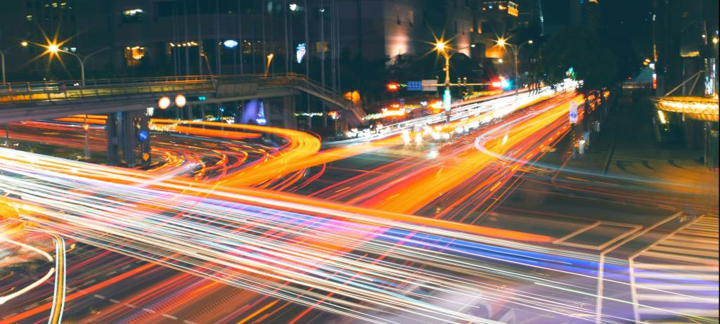 Aufnahme einer verkehrsreichen Kreuzung in Taipei bei Nacht, durch die lange Belichtungszeit hinterlassen die Lichter der Fahrzeuge rote und weiße Spuren.