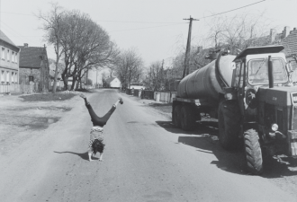 Das schwarz-weiß Bild zeigt eine Person, die auf einer unbefahrenen Landstraße in Beerfelde einen Handstand macht.  