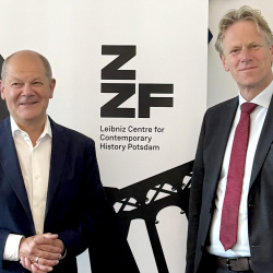 Bundeskanzler a.D. Olaf Scholz und ZZF-Direktor Frank Bösch vor einem Banner mit dem Logo des ZZF.